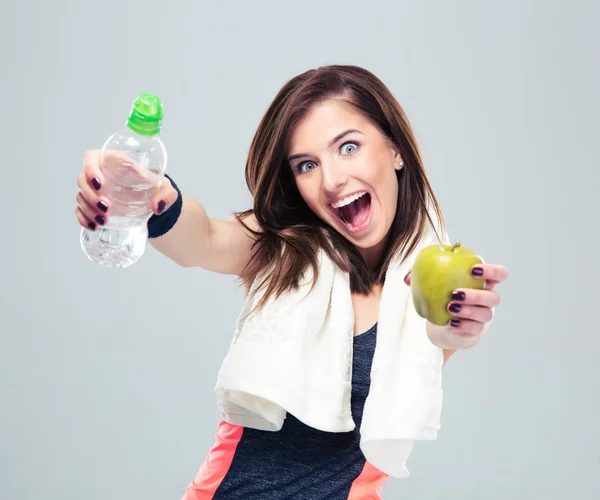 Lustige sportliche Frau hält Apfel und Flasche mit Wasser — Stockfoto