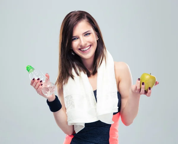 Smiling woman holding apple and bottle with water — Stock Photo, Image