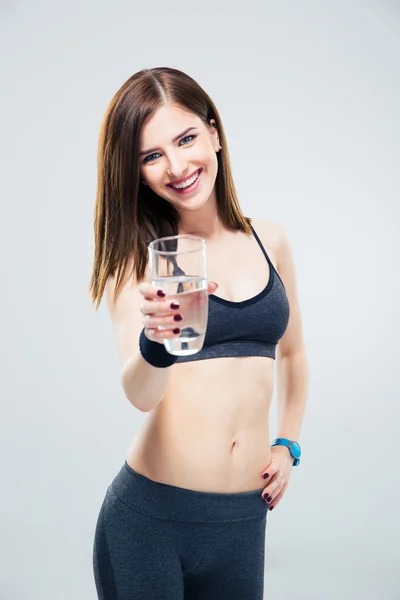 Sorridente donna sportiva dando un bicchiere d'acqua sulla macchina fotografica — Foto Stock
