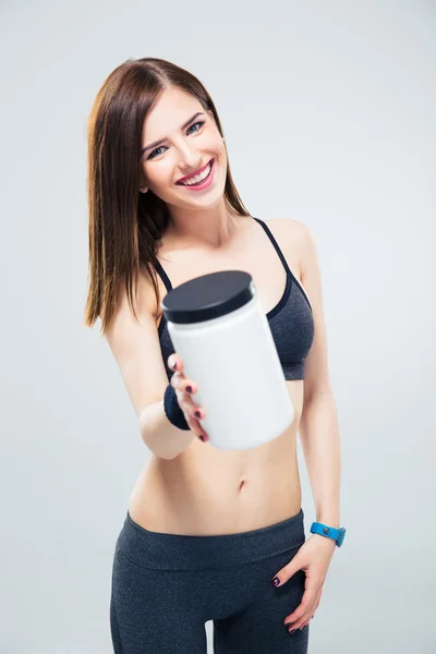 Happy sporty woman giving jar of protein on camera — Stock Photo, Image