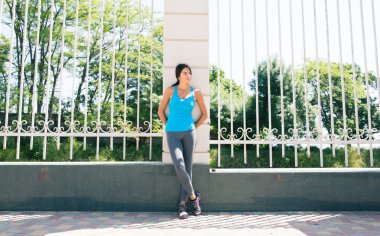 Çit yaslanmış dalgın sportif kadın