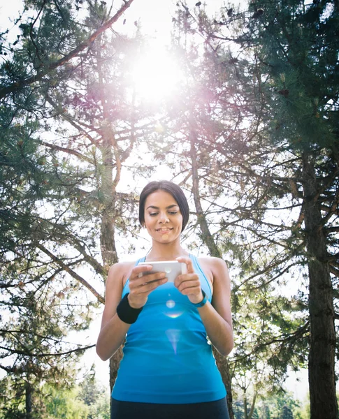 Femme sportive utilisant un smartphone en plein air — Photo