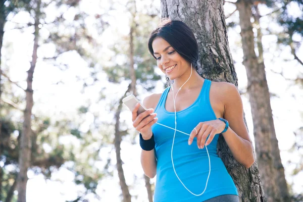 Wanita sporty tersenyum menggunakan smartphone outdoors — Stok Foto