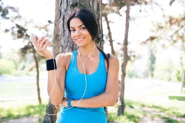 Mujer deportiva feliz sosteniendo teléfono inteligente al aire libre — Foto de Stock