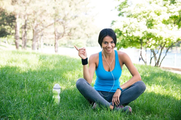 Šťastný fitness žena sedí na zelené trávě — Stock fotografie