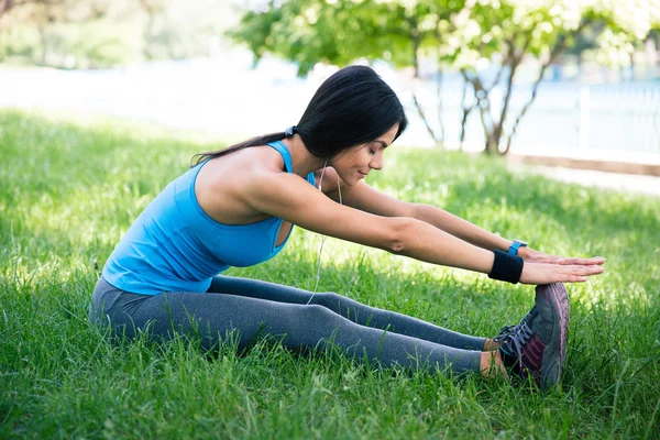 Sportieve vrouw uitrekken op groen gras — Stockfoto