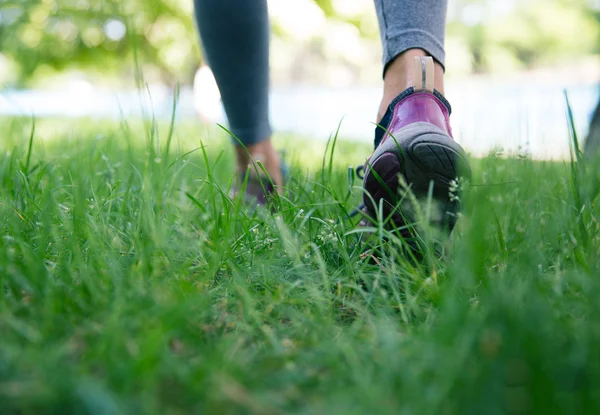 Chaussures sur pieds féminins fonctionnant sur herbe verte — Photo