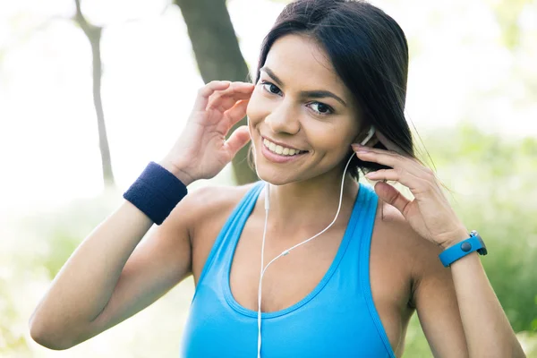 Lächelnde sportliche Frau mit Kopfhörern im Freien — Stockfoto