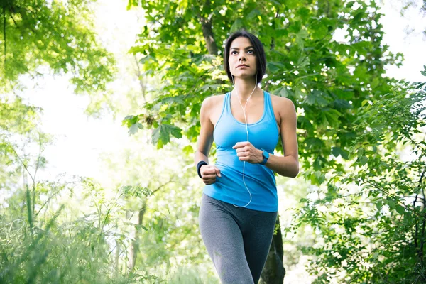 Mujer deportiva en auriculares corriendo — Foto de Stock
