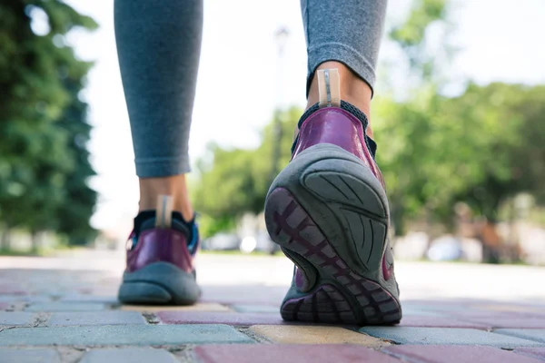 Calçado em pés femininos correndo na estrada — Fotografia de Stock