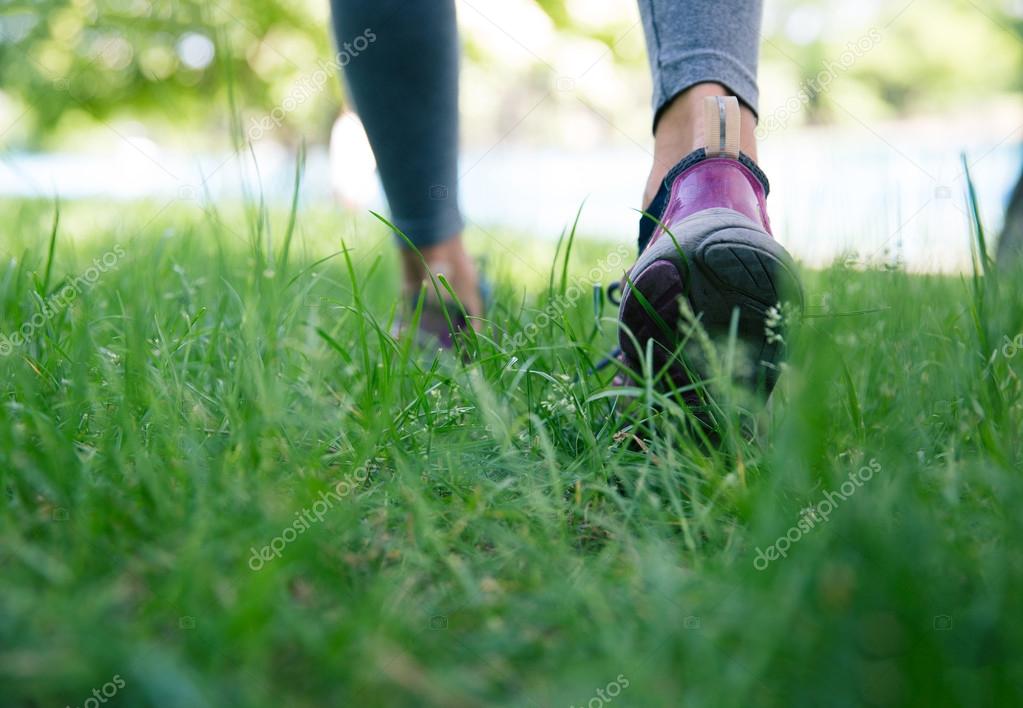Footwear on female feet running on green grass