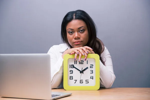 Tired businesswoman sitting at the table with clock — Stock Photo, Image