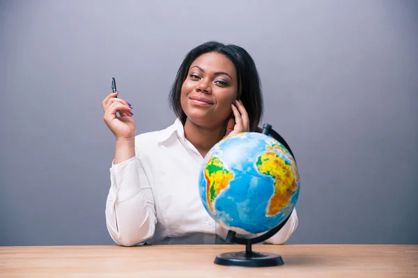 Businesswoman sitting at the table with pen and globe — Stock Photo, Image