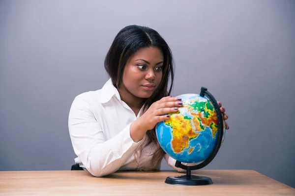 African businesswoman sitting at the table with globe Stock Image