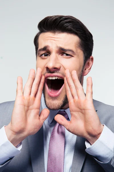 Businessman shouting over gray background — Stock Photo, Image