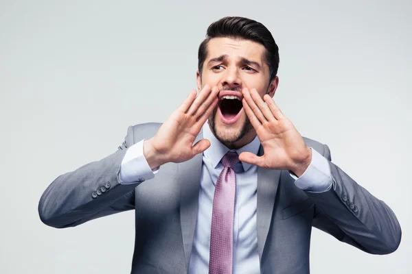Handsome businessman shouting over gray background — Stock Photo, Image
