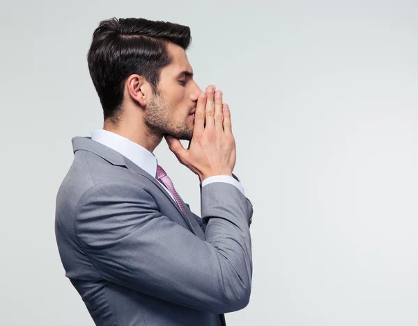 Geschäftsmann betet vor grauem Hintergrund — Stockfoto