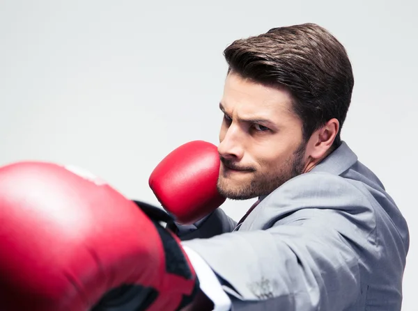 Empresario en guantes de boxeo golpeando a cámara —  Fotos de Stock