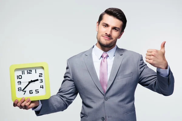 Empresario sosteniendo el reloj y mostrando el pulgar hacia arriba — Foto de Stock