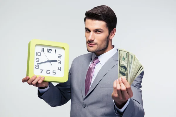 Businessman holding money and clock — Stock Photo, Image