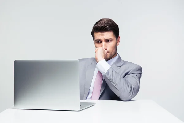 Empresário atencioso sentado à mesa com laptop — Fotografia de Stock