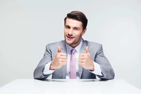 Businessman sitting at the table with thumbs up — Stock Photo, Image