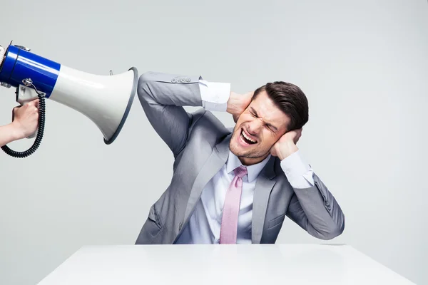 Businessman covering his ears from megaphone — Stock Photo, Image