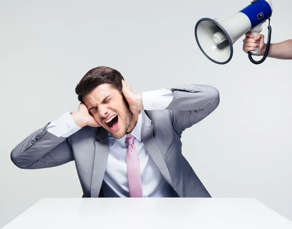 Businessman covering his ears from megaphone — Stock Photo, Image