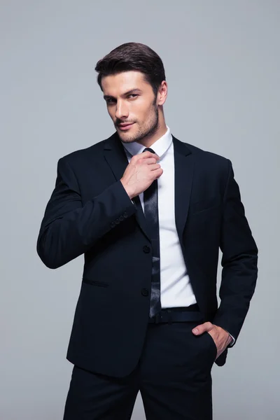 Handsome businessman straightening his tie — Stock Photo, Image