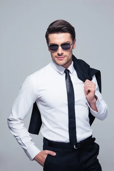 Businessman with jacket on shoulder and sunglasses — Stock Photo, Image