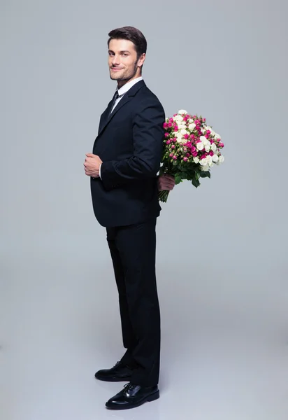 Businessman hiding bouquet of flowers behind his back — Stock Photo, Image