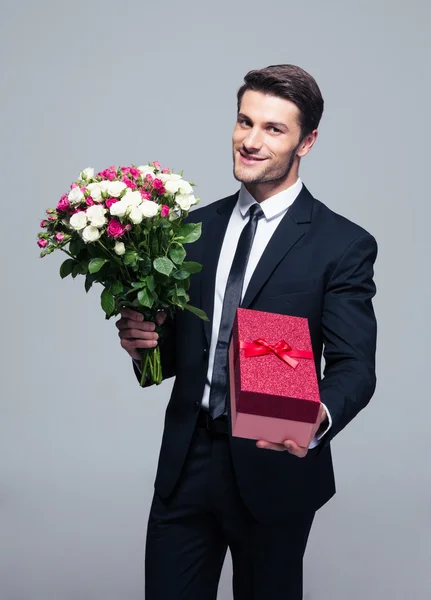 Çiçek ve hediye kutusu ile yakışıklı işadamı — Stok fotoğraf