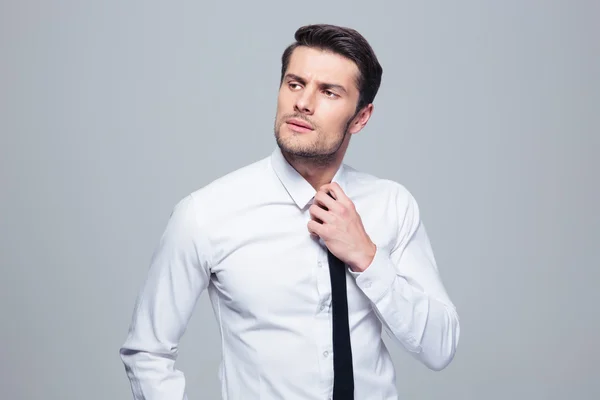 Pensive businessman straightening his tie — Stock Photo, Image