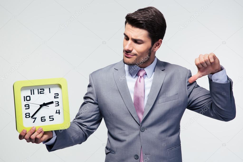 Businessman holding clock and showing thumb down