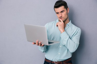 Dizüstü bilgisayar kullanan dalgın casual adam