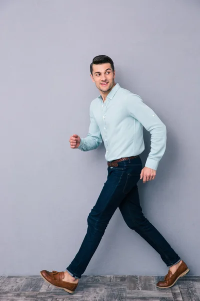 Gelukkig jonge man lopen over grijze achtergrond — Stockfoto