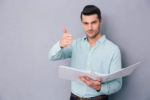 Hombre sosteniendo la carpeta y mostrando el pulgar hacia arriba — Foto de Stock