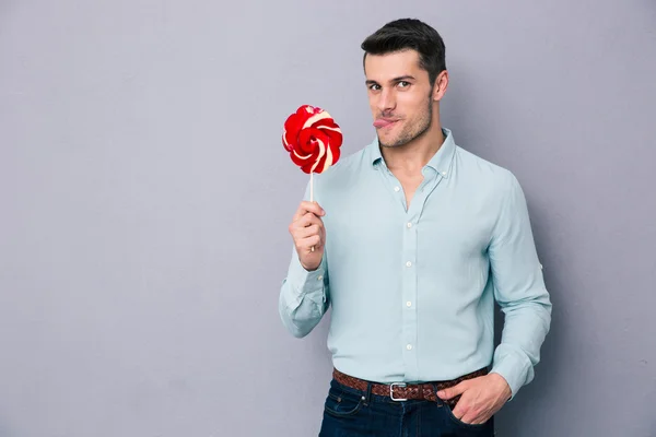 Komik genç adam holding lolipop — Stok fotoğraf