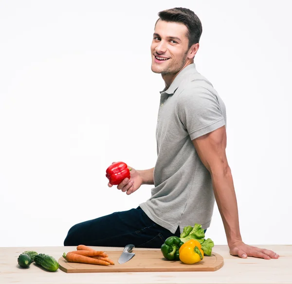 Человек сидит на столе с овощами — стоковое фото
