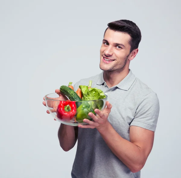 Glad ung man anläggningen skål med grönsaker — Stockfoto