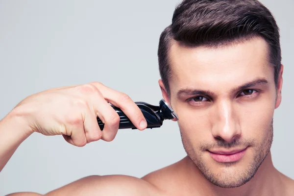 Young man shaving with electric razor — Stock Photo, Image