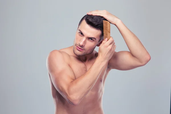 Schöner junger Mann kämmt seine Haare — Stockfoto