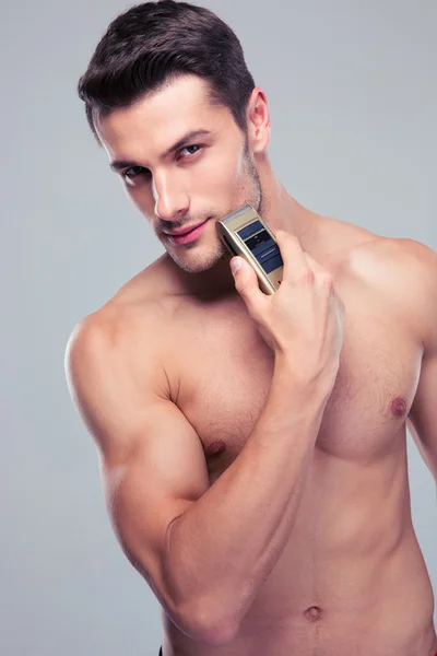Muscular man shaving with electric razor — Stock Photo, Image