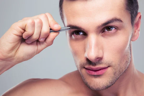 Hombre quitando pelos de cejas con pinzas — Foto de Stock