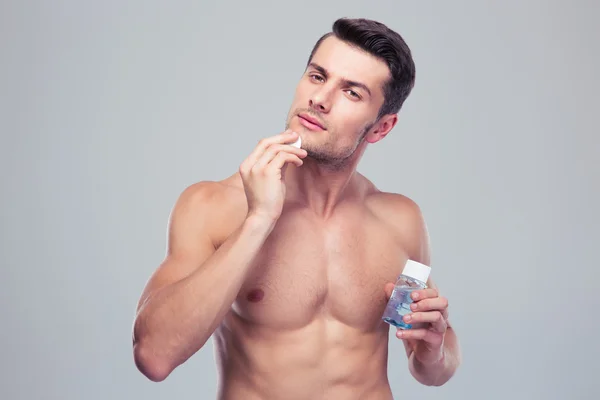 Man applying lotion after shave on face — Stock Photo, Image