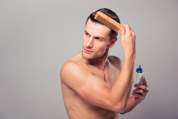 Schöner Mann, der Haarspray auf sein Haar aufträgt — Stockfoto