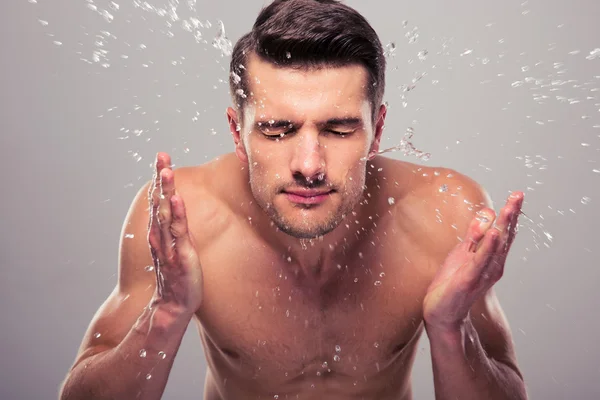 Mladý muž stříkající vody na obličej — Stock fotografie