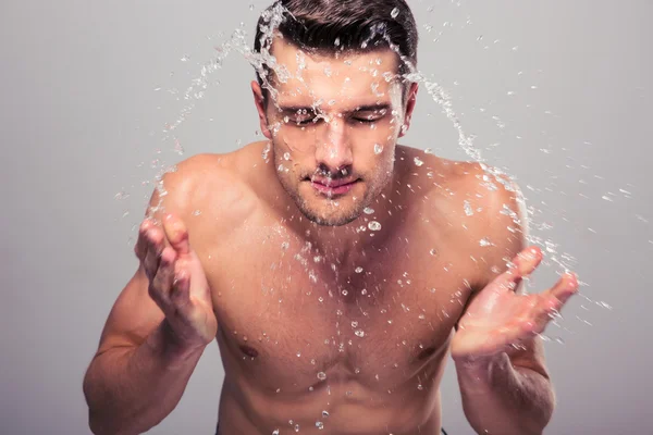 Junger Mann sprüht sich Wasser ins Gesicht — Stockfoto
