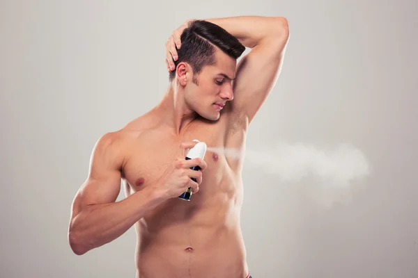 Pohledný muž postřik deodorant — Stock fotografie