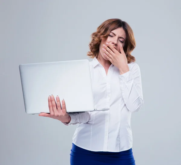 Businesswoman holding laptop and yawning — Stock Photo, Image